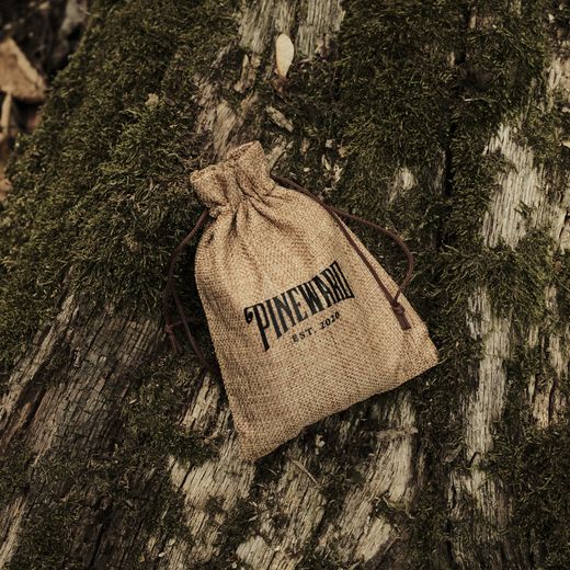 A Pineward burlap pouch on a mossy log