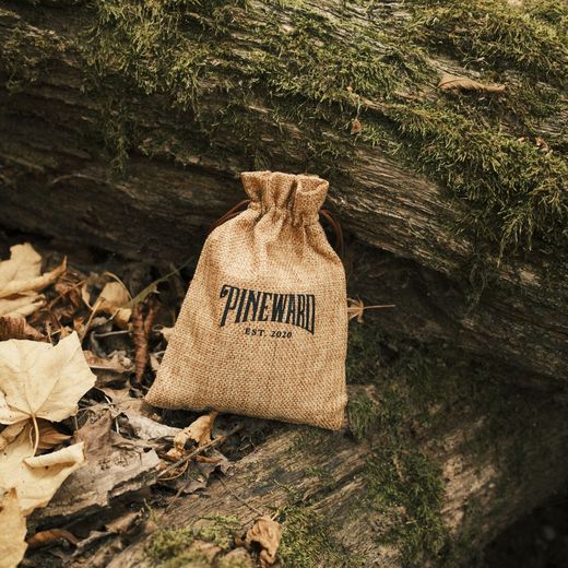 A Pineward burlap pouch among fallen leaves on a log